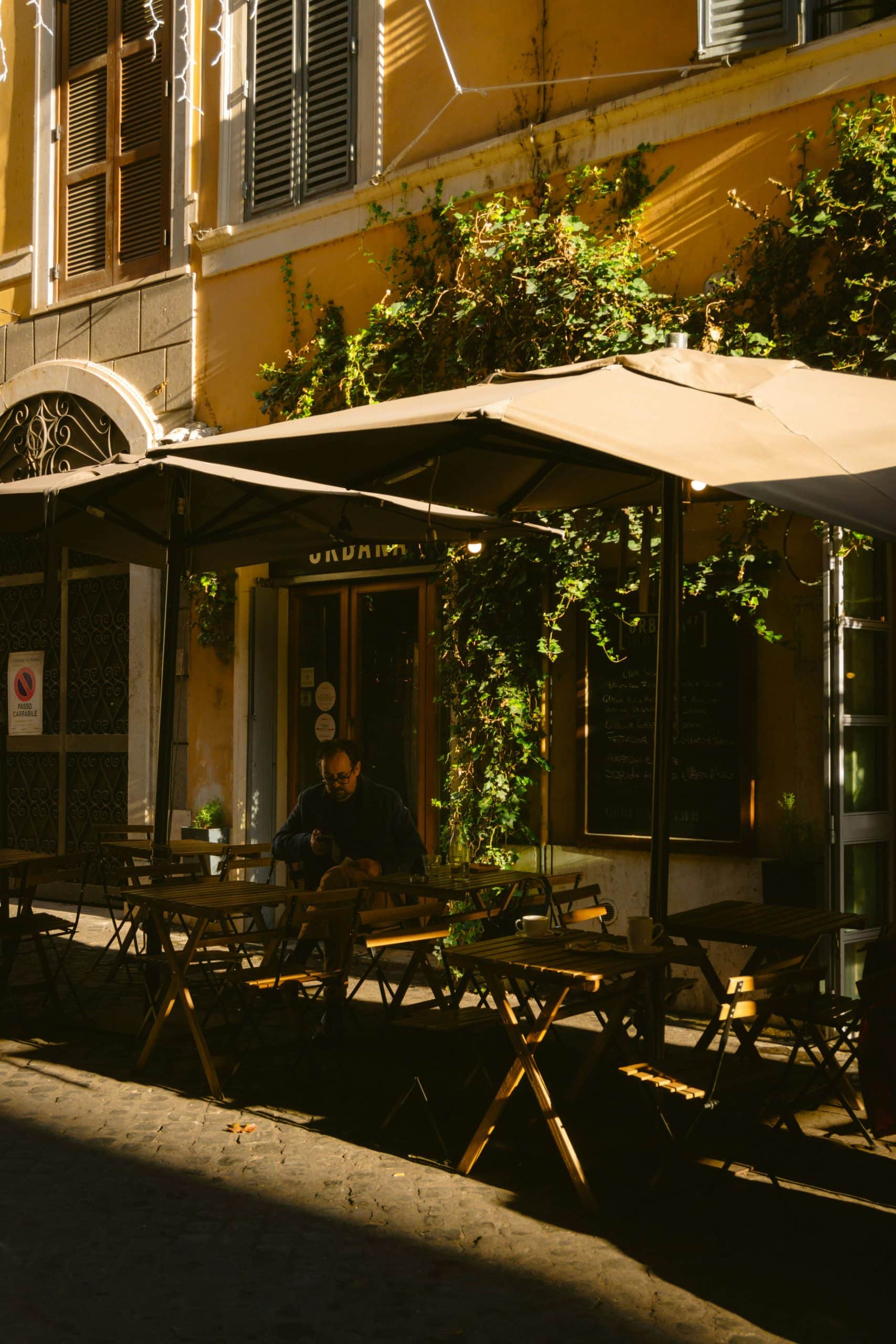 A solitary person sits at a quaint outdoor café on a sunny day, surrounded by the warm hues of a cityscape. Tips Before You Visit Italy!