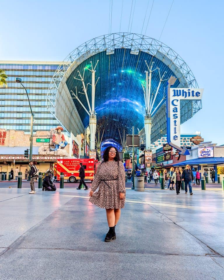 A woman standing in a street with a blue umbrella.