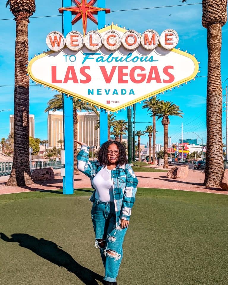 A woman standing in front of a sign.