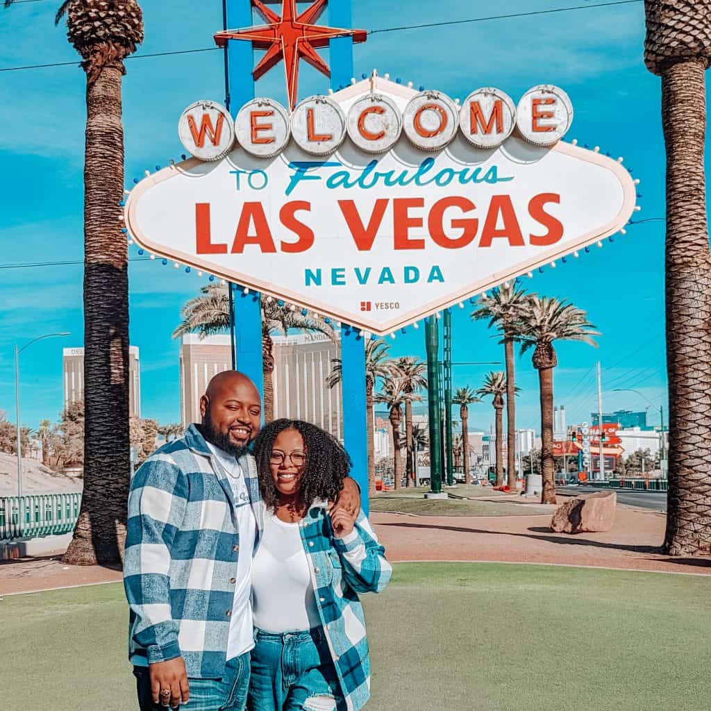 A man and woman standing in front of a sign.