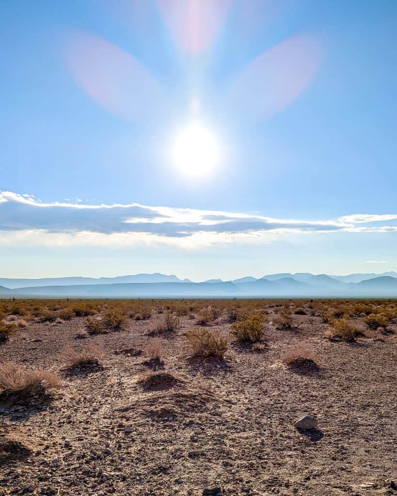The sun shines over a deserted area with mountains in the distance.