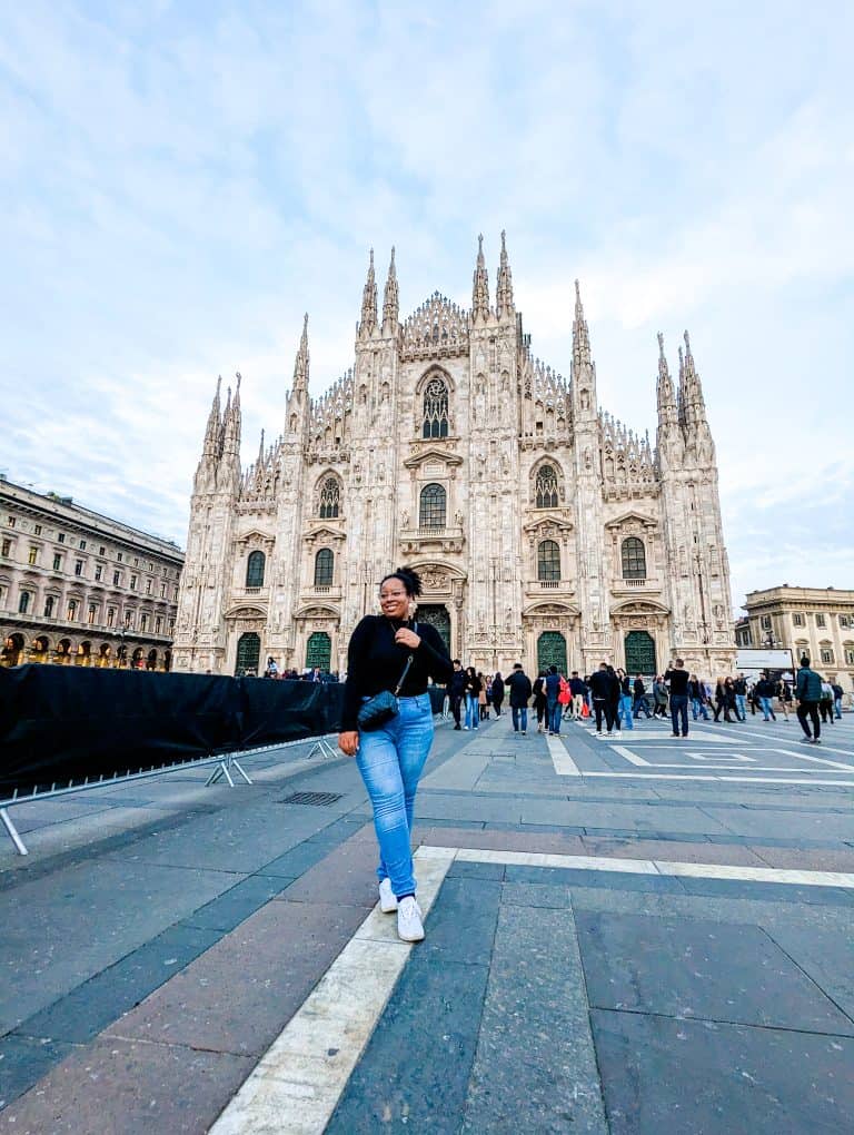 A woman walking in front of a cathedral in milan.