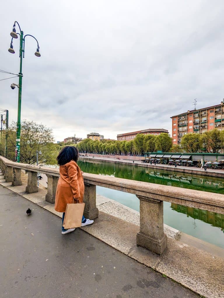 A woman is standing on a railing near a river.