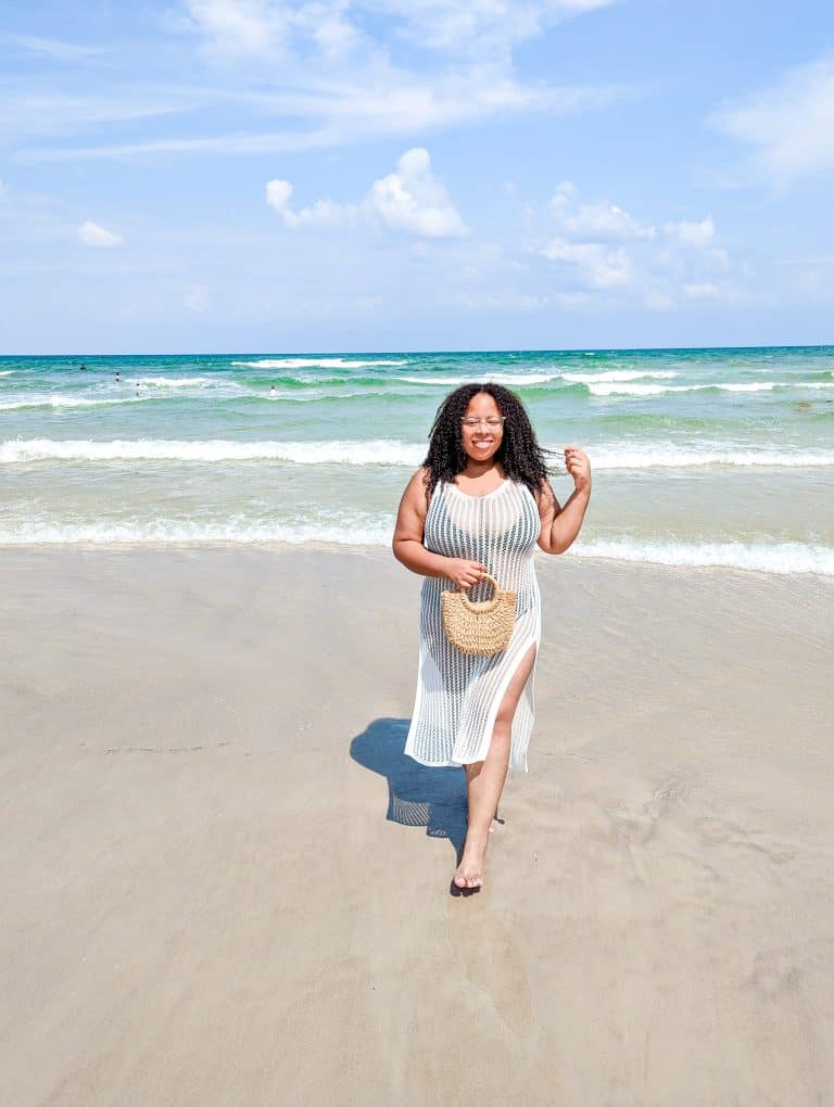 A woman in a white dress walking on the beach.