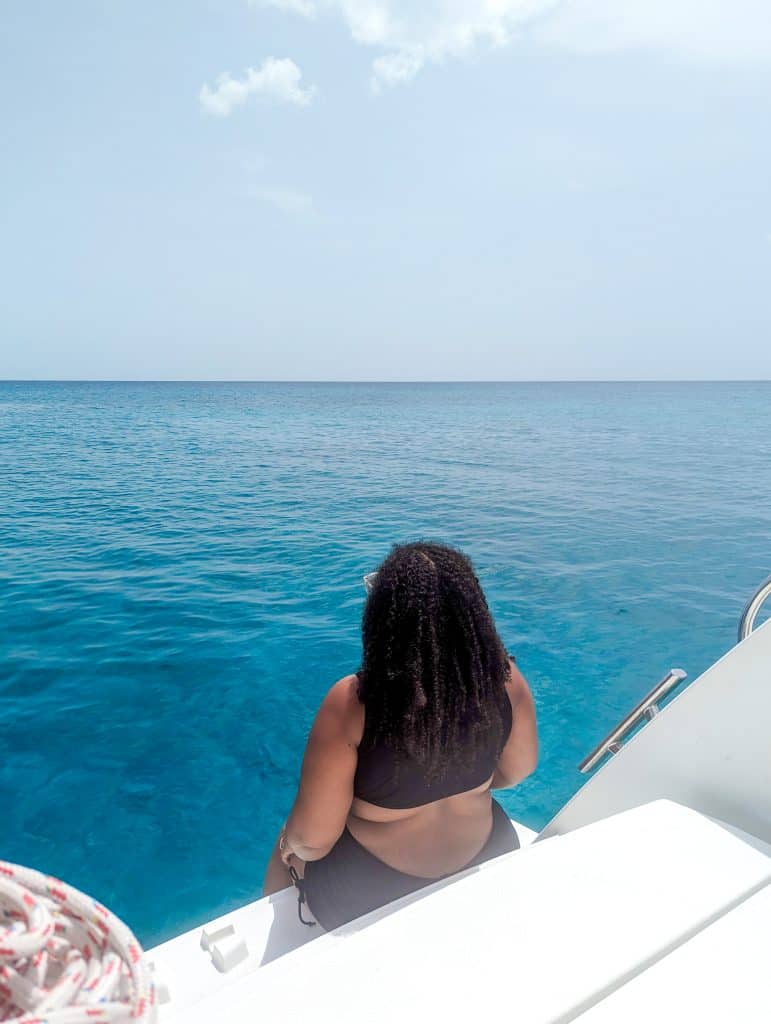 A woman in a bikini sitting on the deck of a boat.