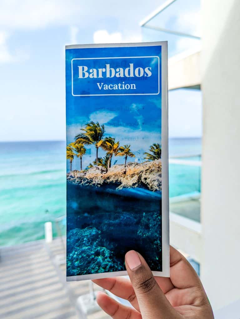 A person holding up a brochure for barbados vacation.