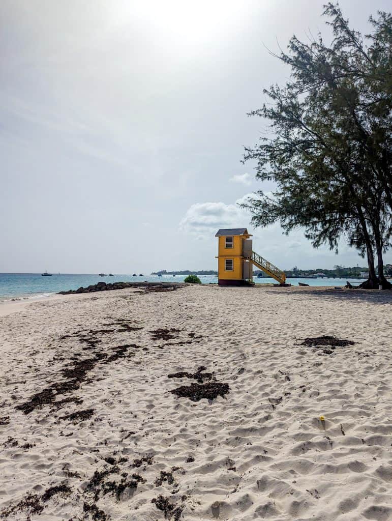 A yellow lifeguard tower sits on a sandy beach.