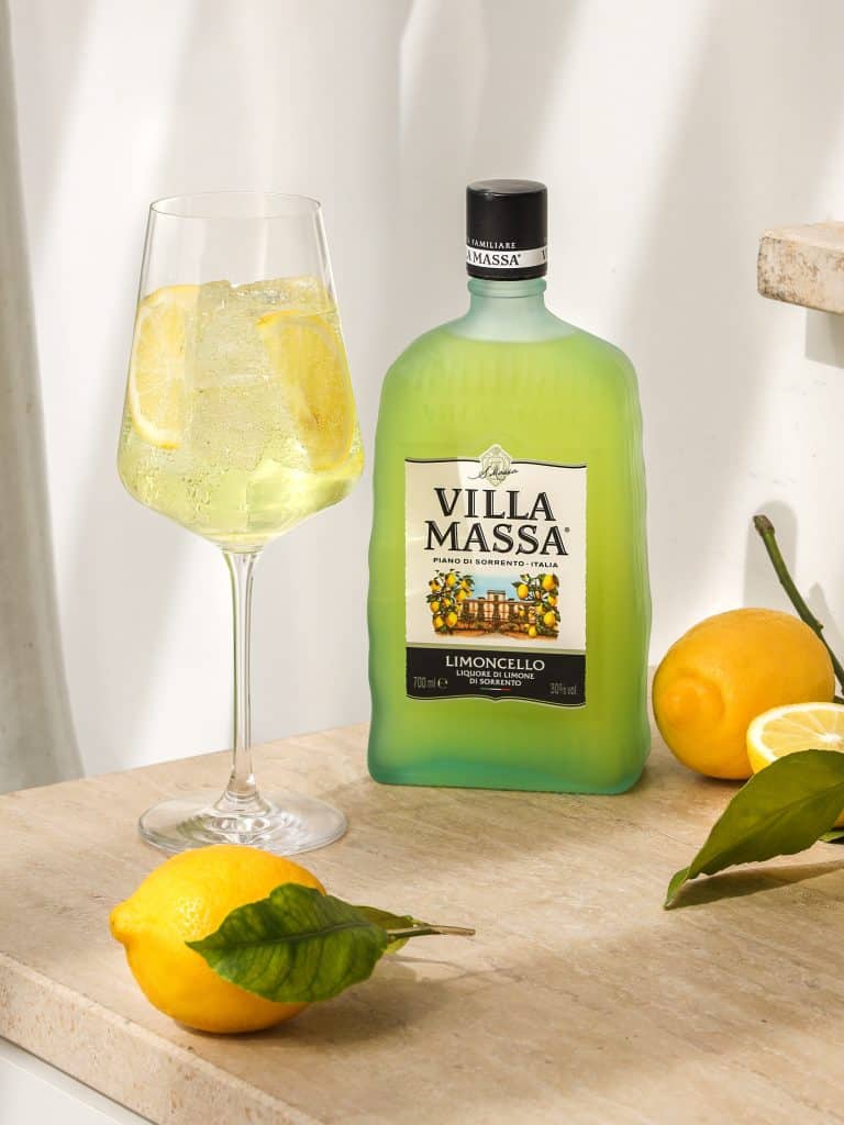 A glass of lemonade next to a bottle of limoncello.