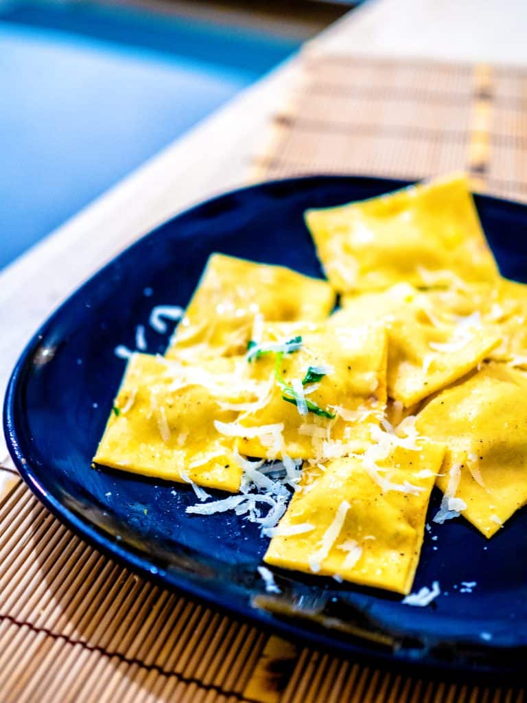 Ravioli on a blue plate with parmesan.