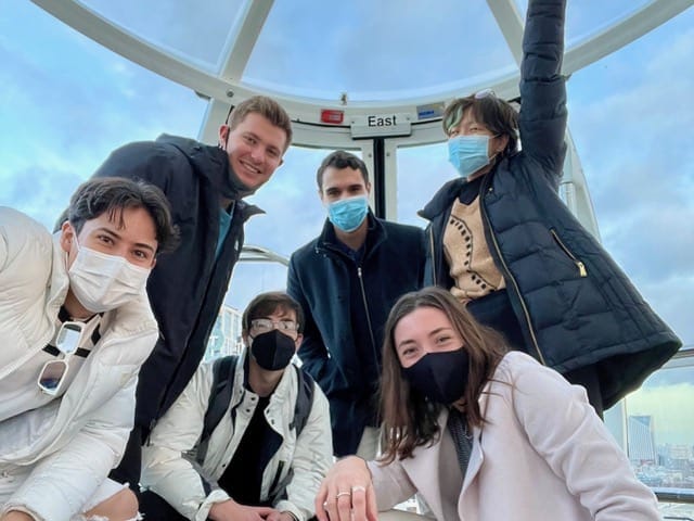 A group of people wearing face masks on top of the london eye.