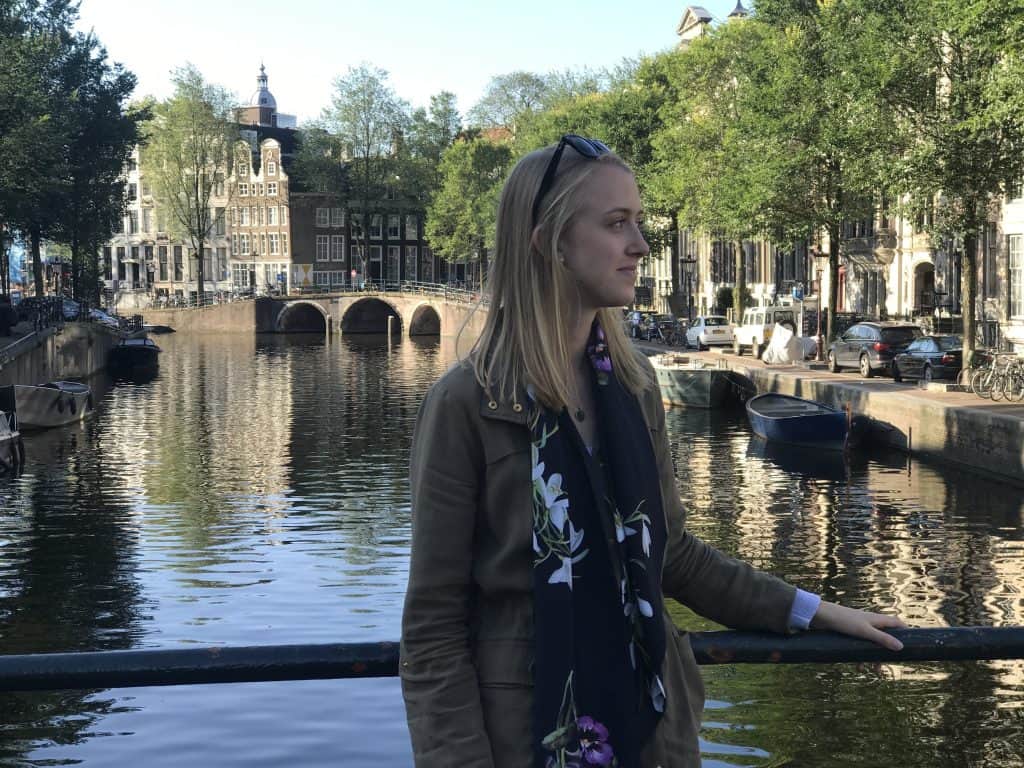 A woman standing next to a canal in amsterdam.