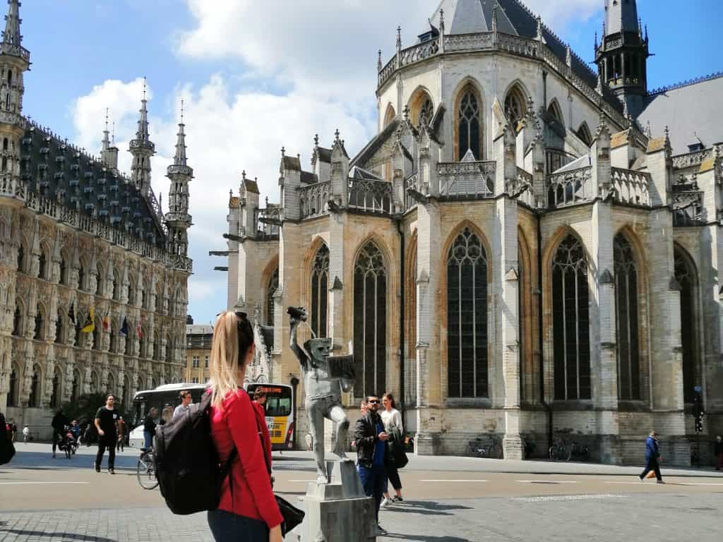 A woman is standing in front of an ornate building.
