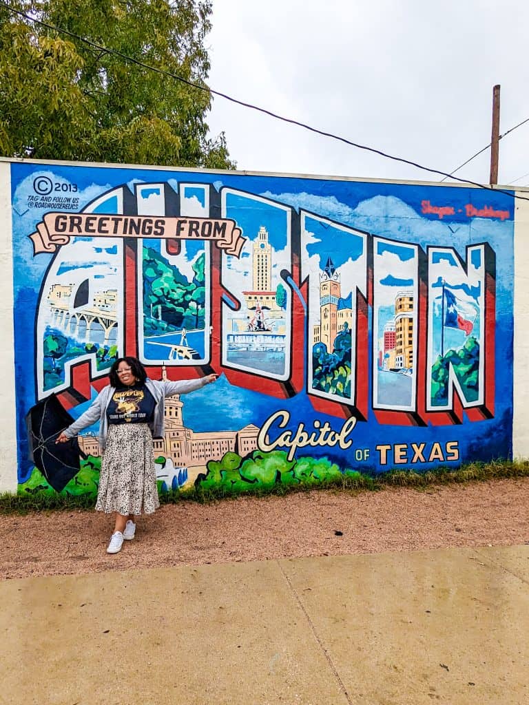 A woman standing in front of a mural of austin.