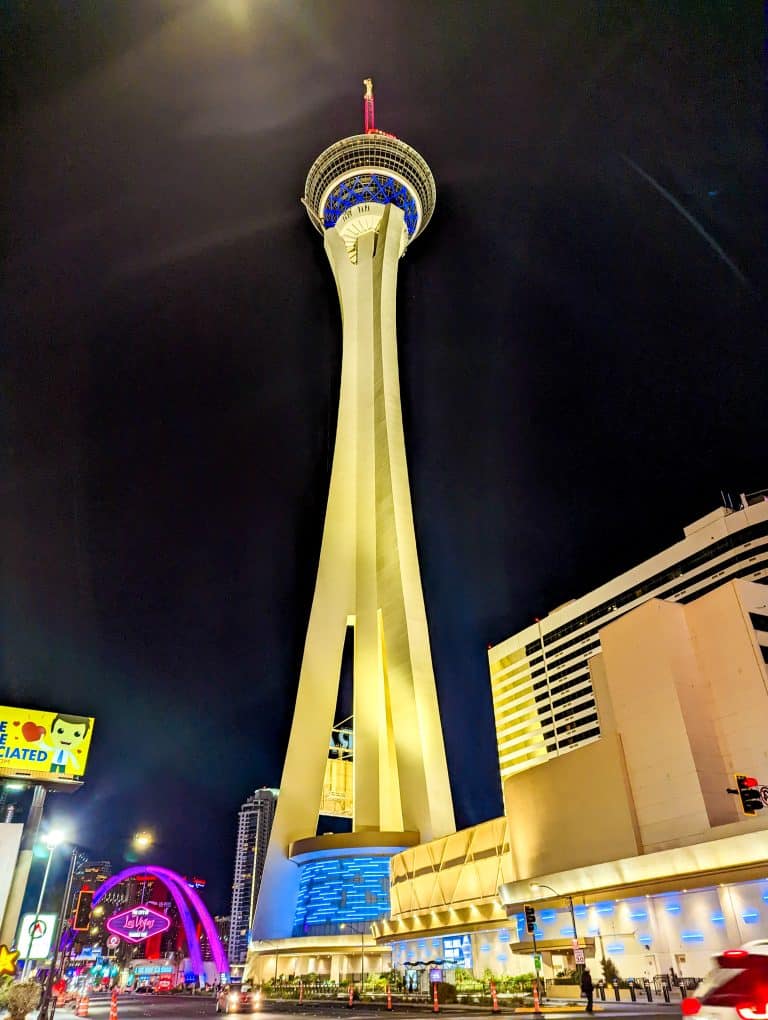 Illuminated tower at night with surrounding city lights.