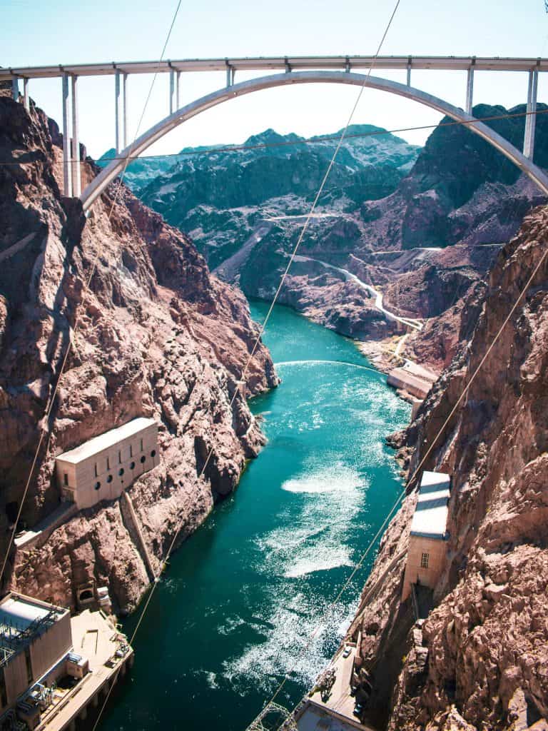 Arch bridge spanning over a river gorge with rocky terrain on both sides, offering things to do at Hoover Dam nearby.