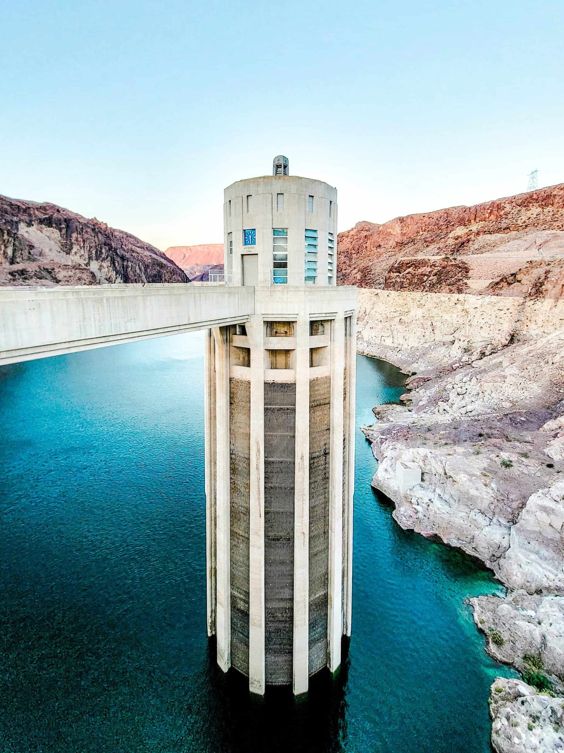 Intake tower at a dam with blue water and visible waterline marks.