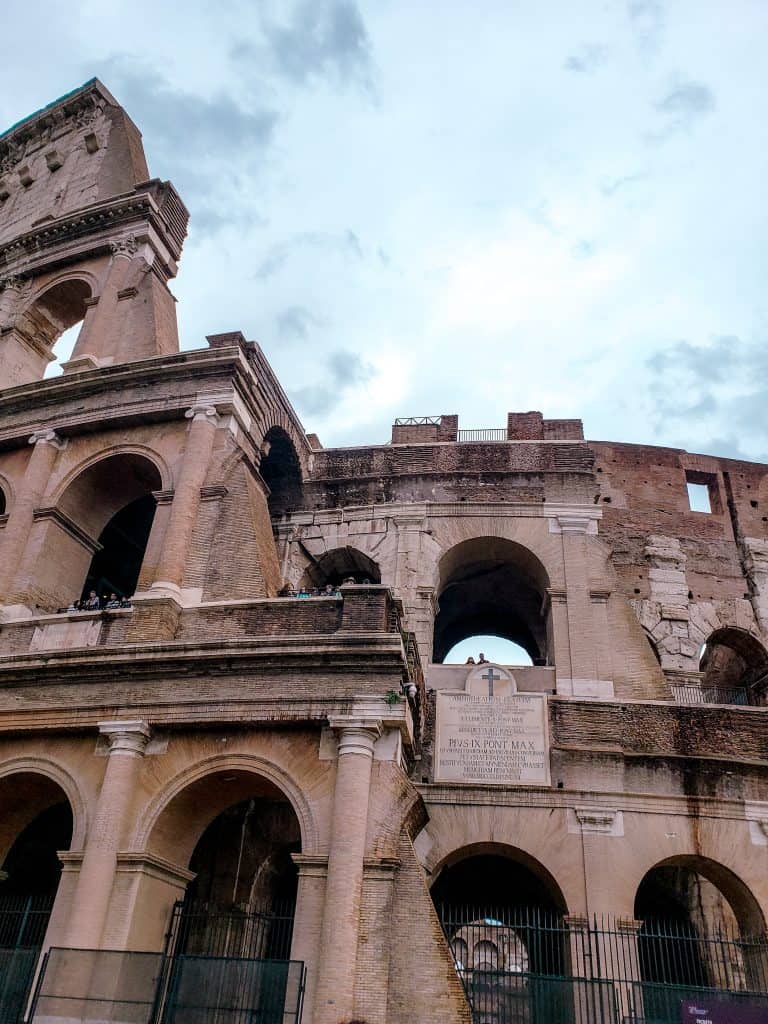 Partial view of the colosseum's exterior, capturing the best way to see the colosseum with a cloudy sky in the background.