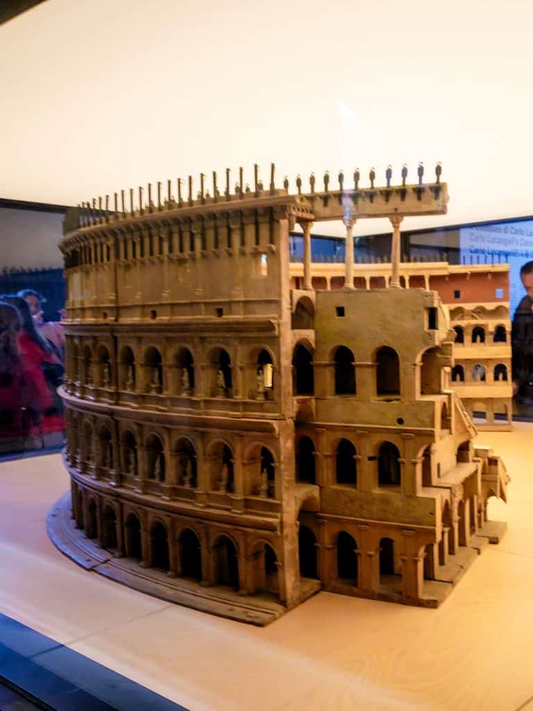 A model of the colosseum on display is the best way to see the colosseum, with soft lighting in the background.