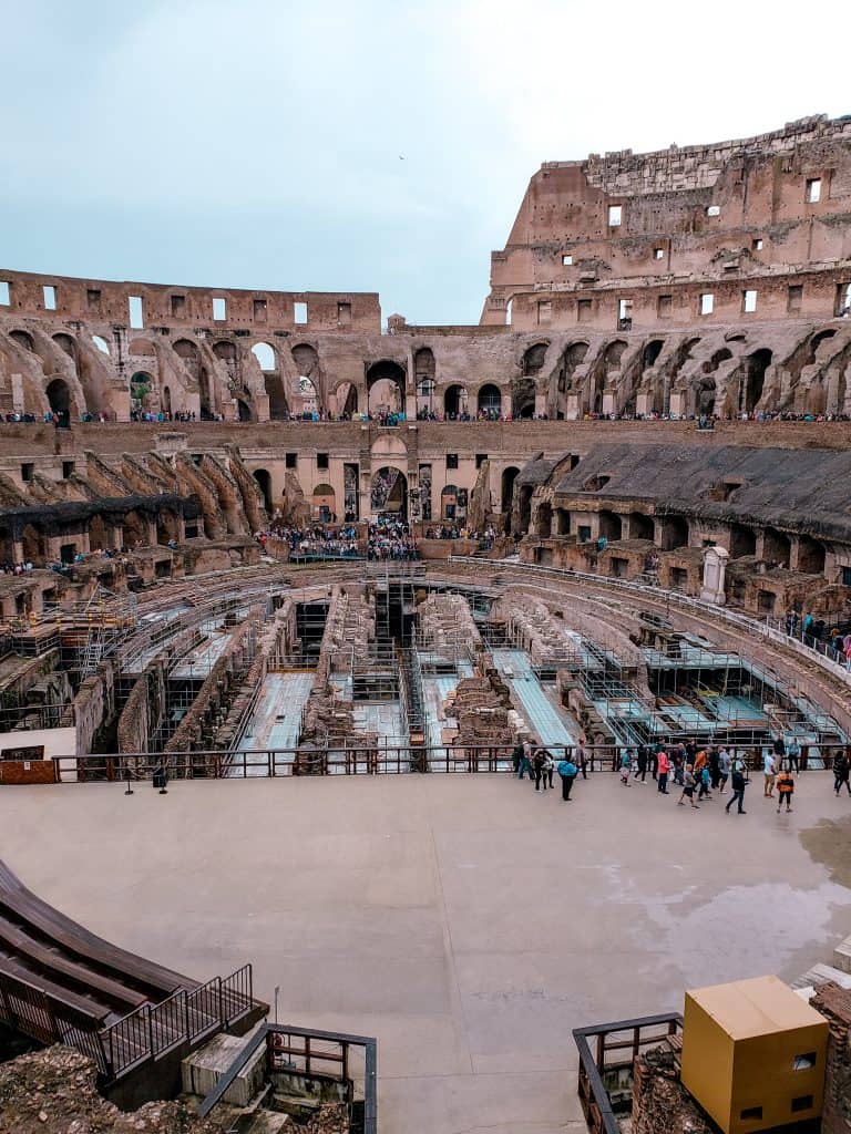 Interior view of the colosseum in Rome, showing the best way to see the central arena, underground structures, and surrounding spectator stands.