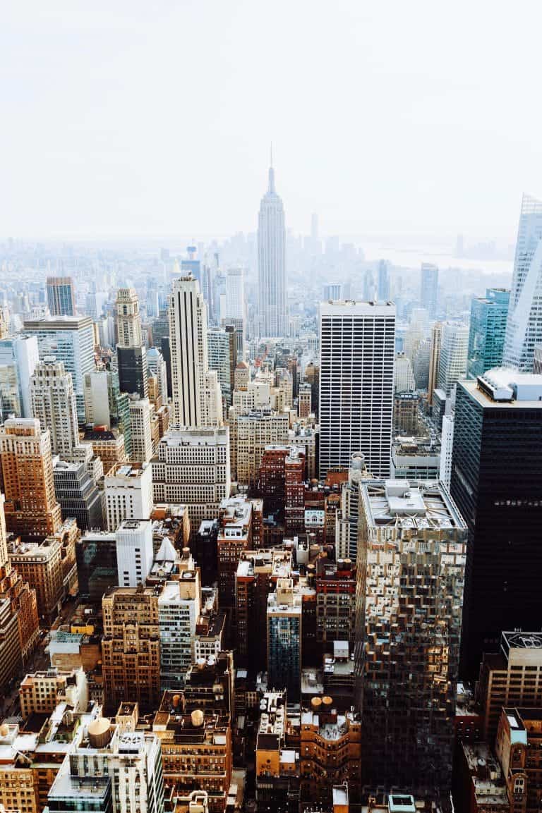 Aerial view of New York City’s vibrant cityscape, with numerous skyscrapers and a tall, central tower under a clear sky—a must-see on any bucket list.